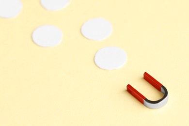 Photo of Magnet attracting paper circles on beige background, closeup