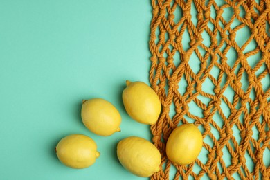 Photo of Macrame shopping bag and lemons on turquoise background, flat lay. Space for text