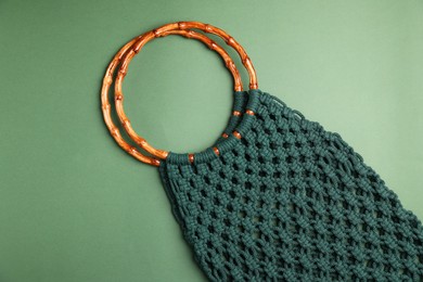 Photo of Macrame shopping bag with wooden handles on green background, top view