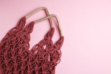 Photo of Macrame shopping bag on pink background, top view. Space for text