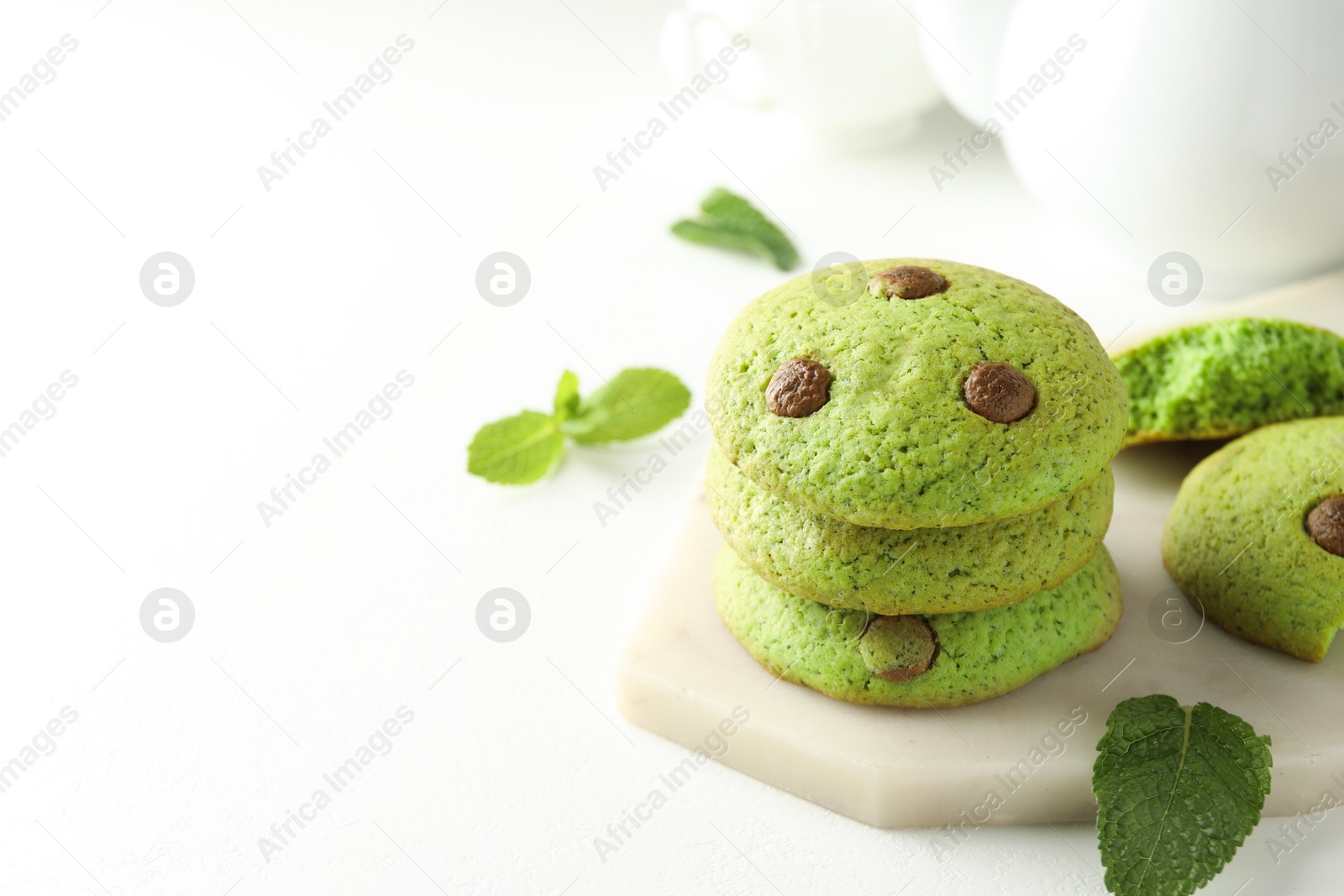 Photo of Delicious mint chocolate chip cookies on white table, closeup. Space for text