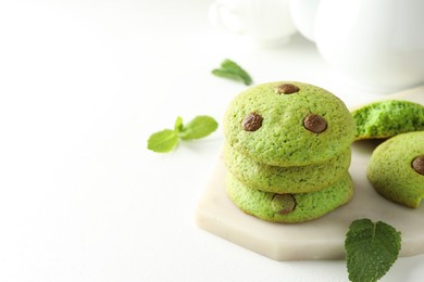 Photo of Delicious mint chocolate chip cookies on white table, closeup. Space for text