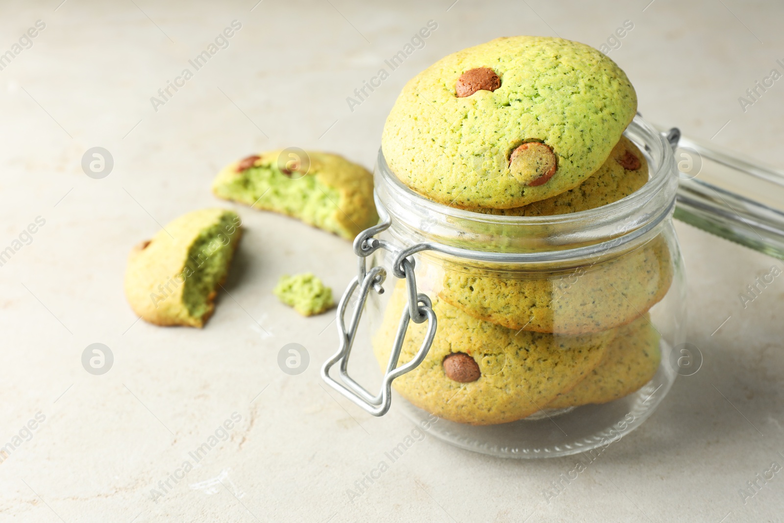 Photo of Delicious mint chocolate chip cookies in jar on light table, closeup