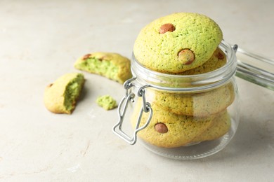 Photo of Delicious mint chocolate chip cookies in jar on light table, closeup