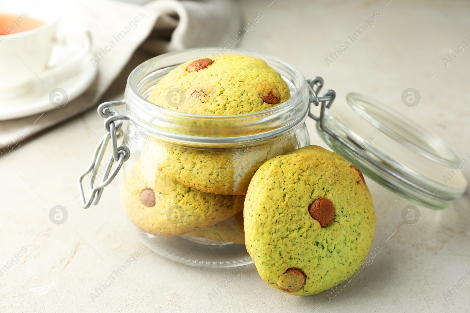 Photo of Delicious mint chocolate chip cookies in jar on light table, closeup