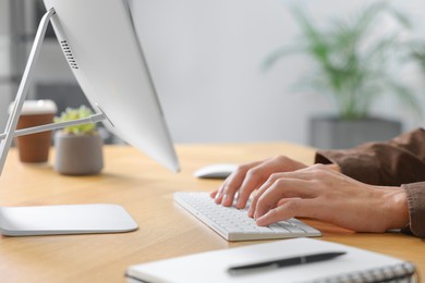 Photo of Man working on computer at wooden desk in office, closeup