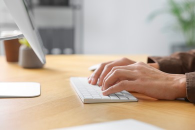 Photo of Man working on computer at wooden desk in office, closeup