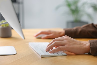 Photo of Man working on computer at wooden desk in office, closeup