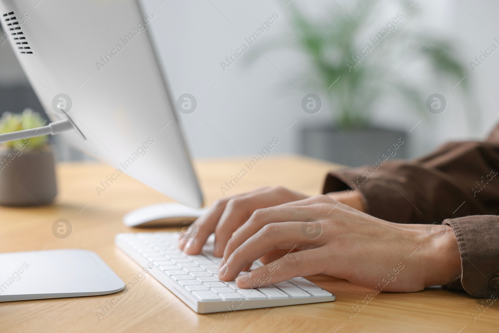 Photo of Man working on computer at wooden desk in office, closeup