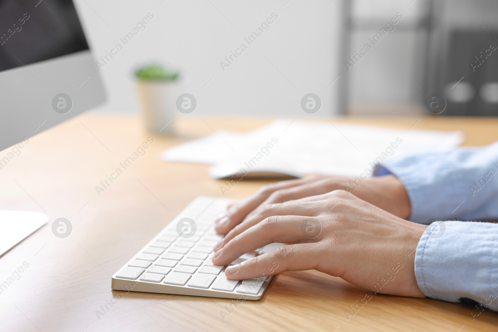 Photo of Man working on computer at wooden desk in office, closeup