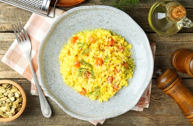 Photo of Delicious pumpkin risotto served on wooden table, flat lay