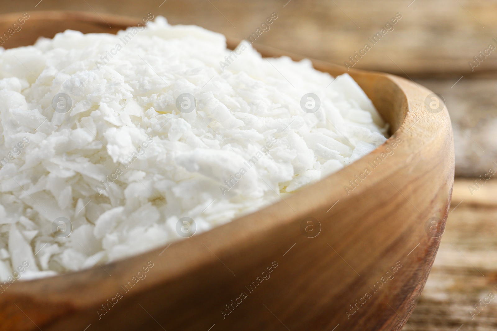 Photo of White soy wax flakes in bowl on table, closeup