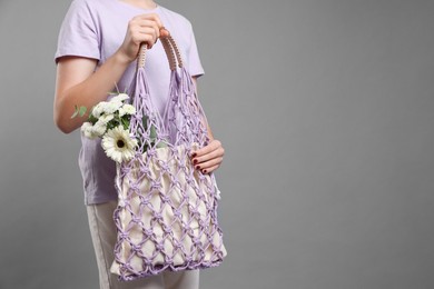 Photo of Teenage girl with handmade macrame bag on grey background, closeup. Space for text