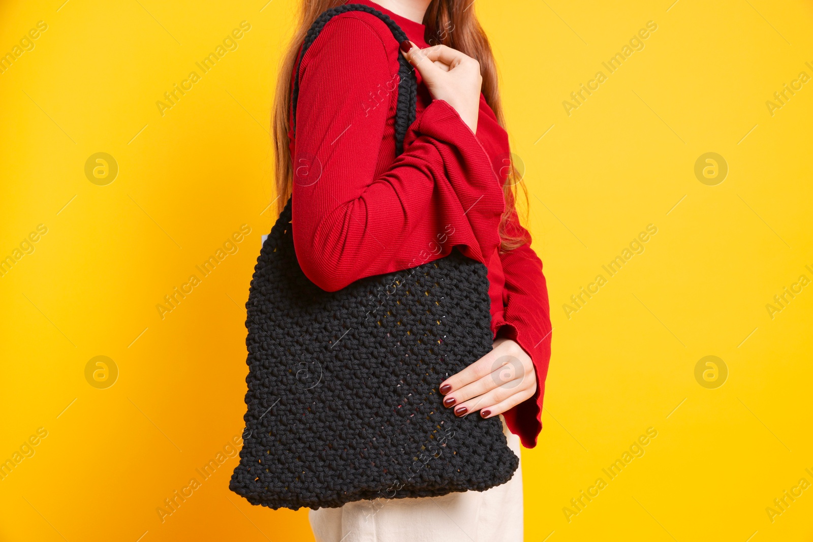 Photo of Teenage girl with handmade macrame bag on yellow background, closeup