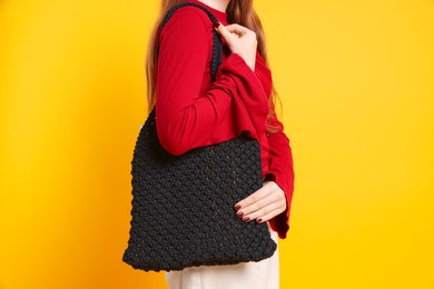 Photo of Teenage girl with handmade macrame bag on yellow background, closeup