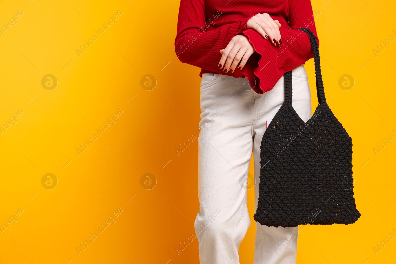 Photo of Teenage girl with handmade macrame bag on yellow background, closeup. Space for text