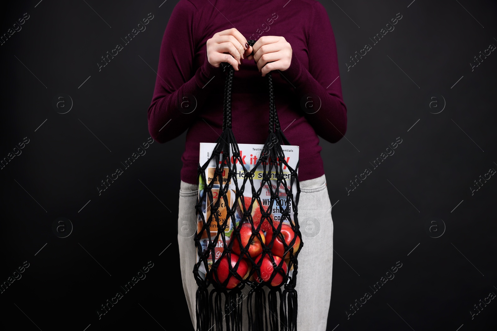 Photo of Teenage girl with handmade macrame bag on black background, closeup