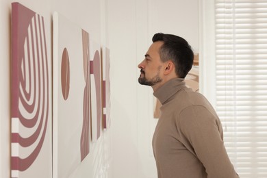 Photo of Man studying beautiful artwork in modern gallery