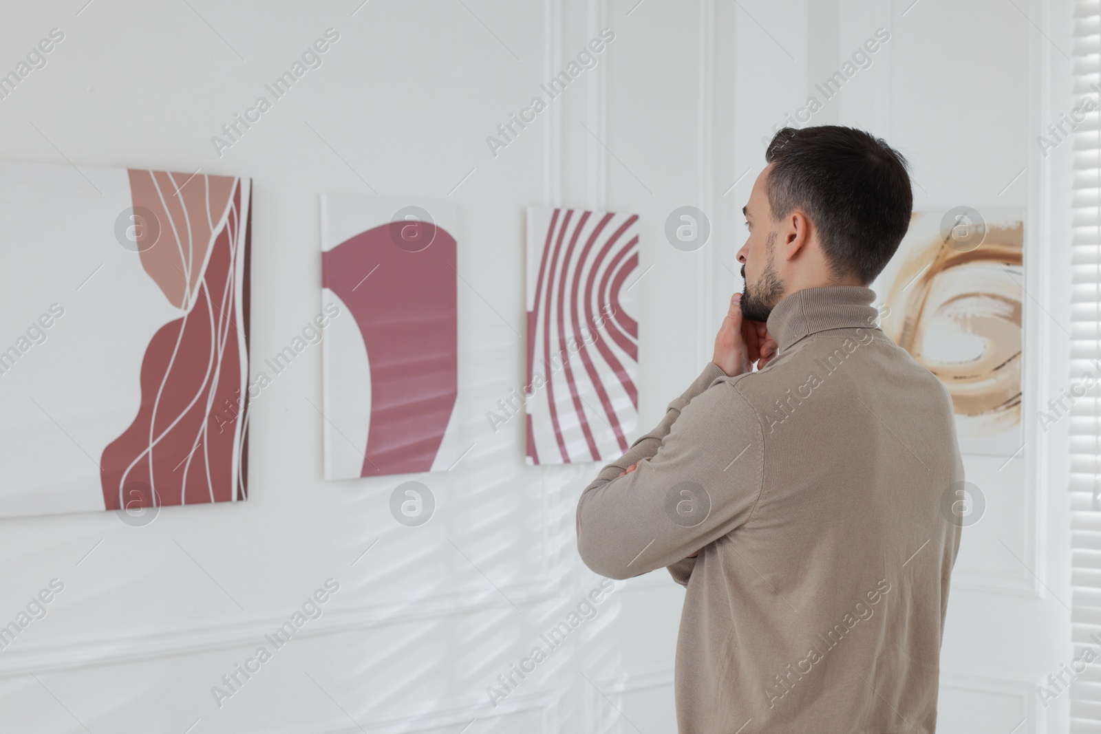 Photo of Man studying beautiful artwork in modern gallery