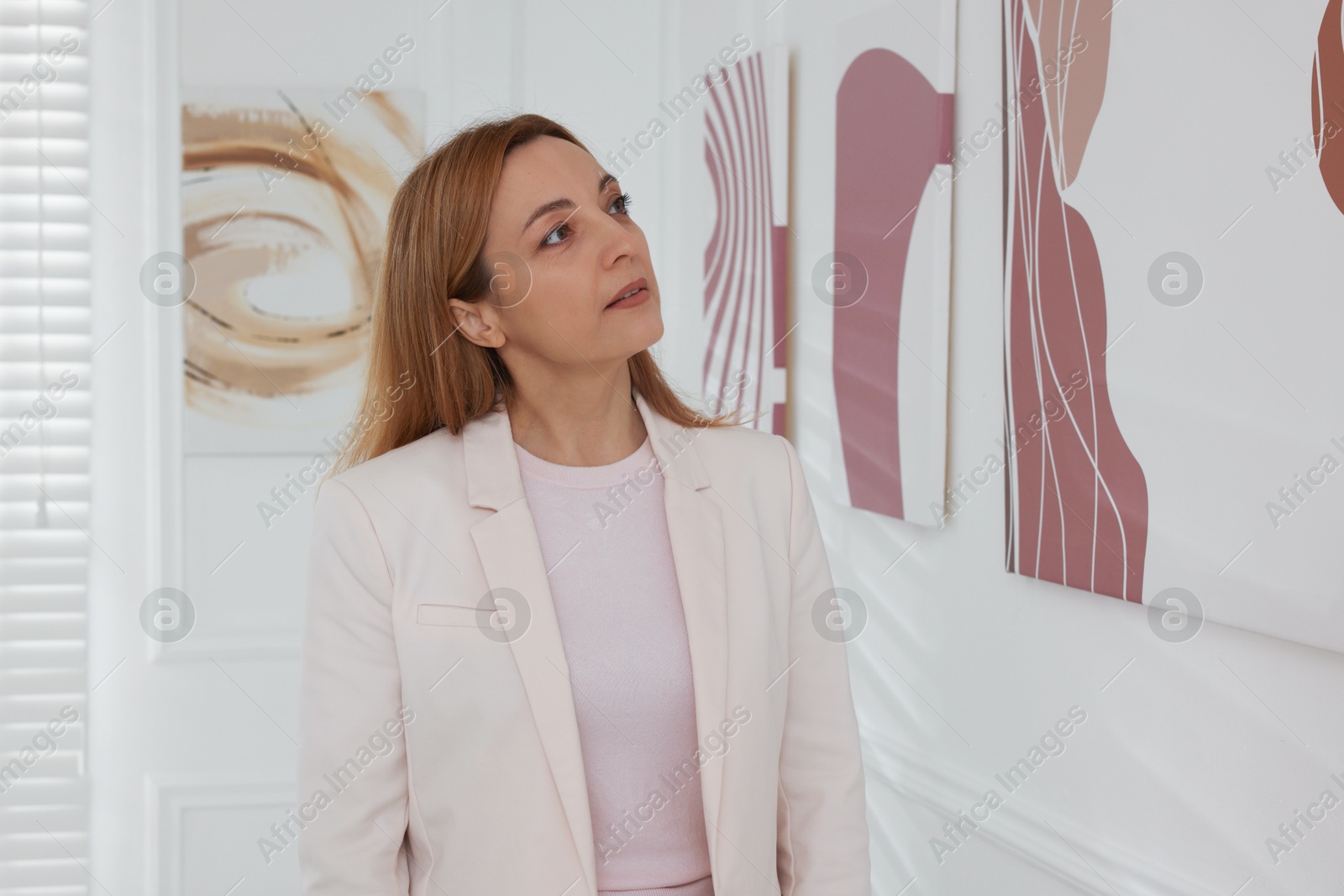 Photo of Woman studying beautiful artwork in modern gallery