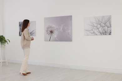 Woman studying beautiful artwork in modern gallery