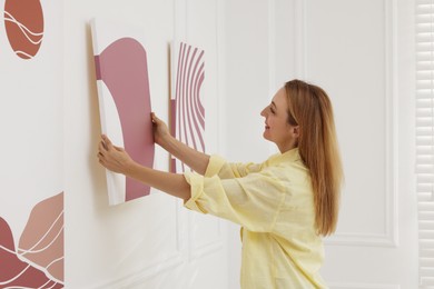 Photo of Woman hanging painting on wall in art gallery