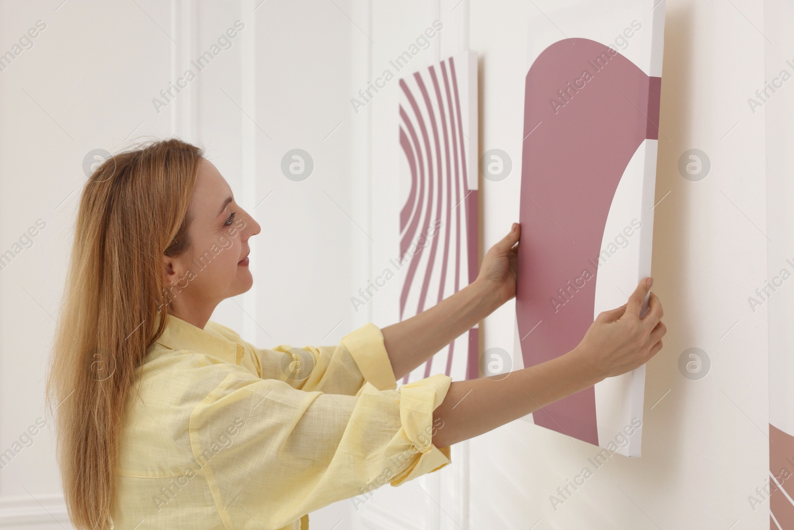 Photo of Woman hanging painting on wall in art gallery