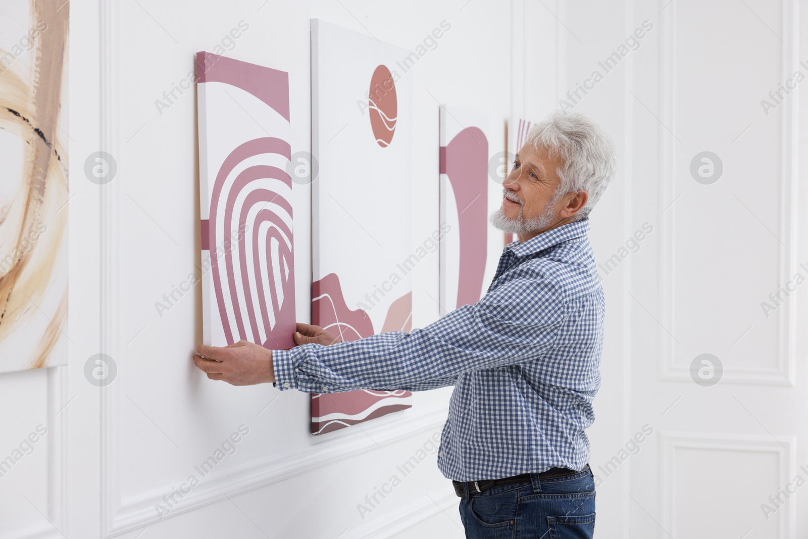 Photo of Man hanging painting on wall in art gallery