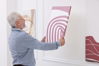 Photo of Man hanging painting on wall in art gallery