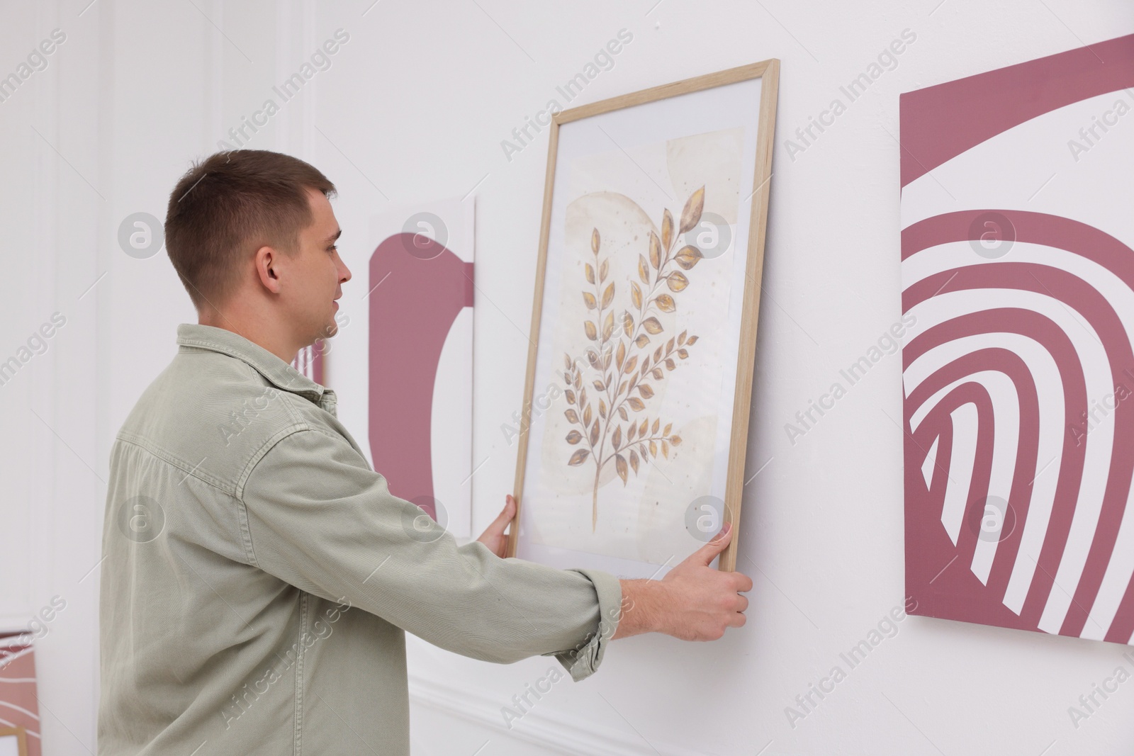 Photo of Man hanging painting on wall in art gallery