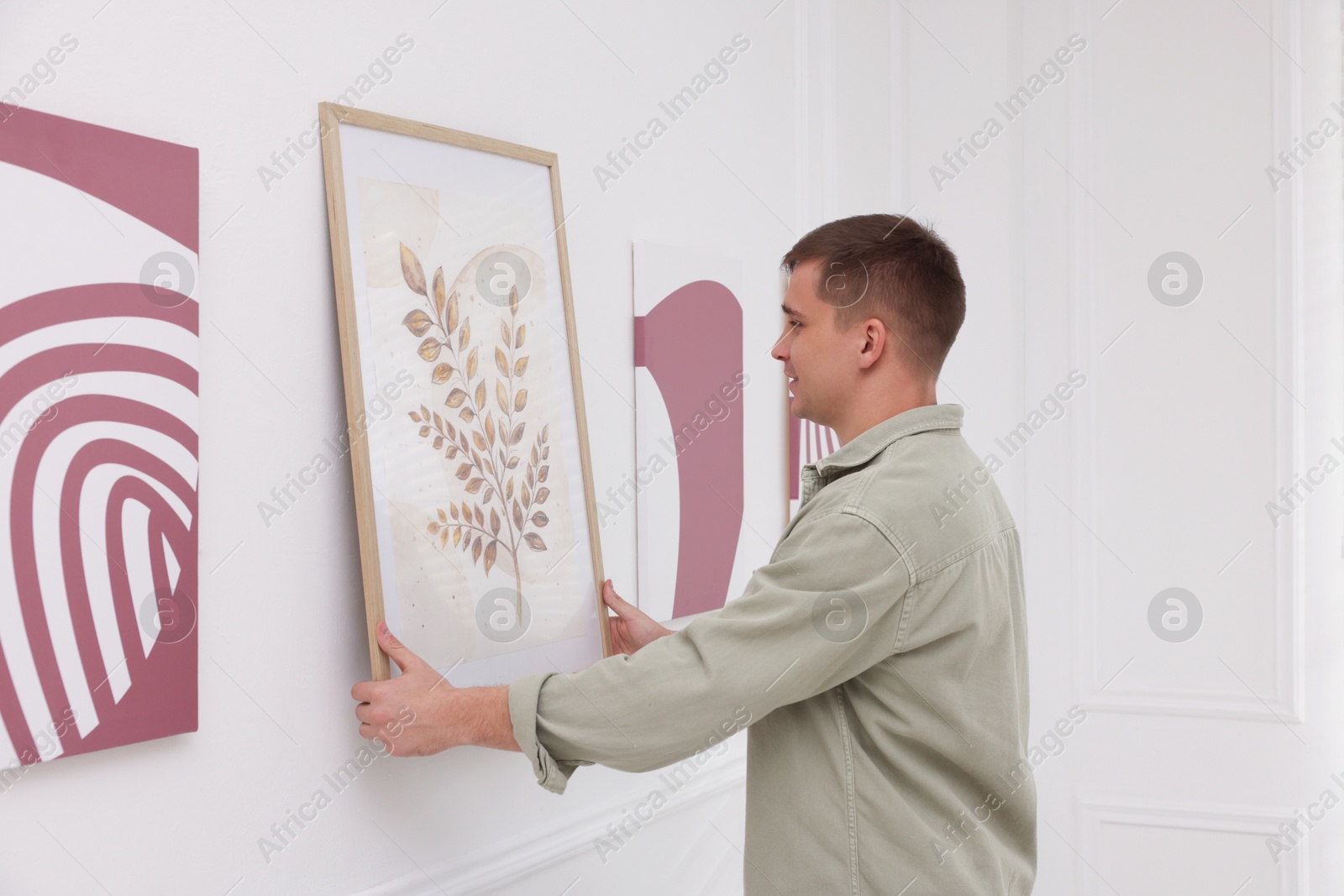 Photo of Man hanging painting on wall in art gallery