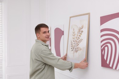 Photo of Man hanging painting on wall in art gallery