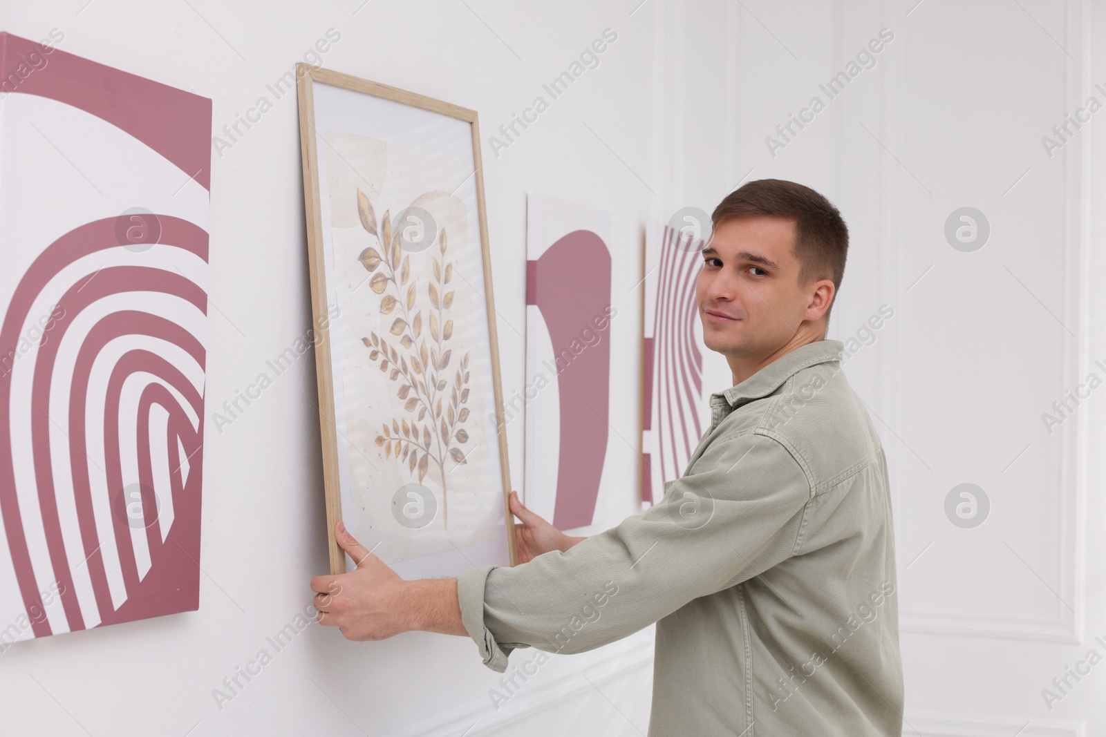 Photo of Man hanging painting on wall in art gallery