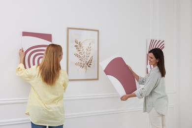 Photo of Women hanging paintings on wall in art gallery