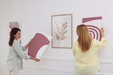 Photo of Women hanging paintings on wall in art gallery