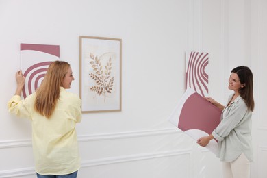 Photo of Women hanging paintings on wall in art gallery