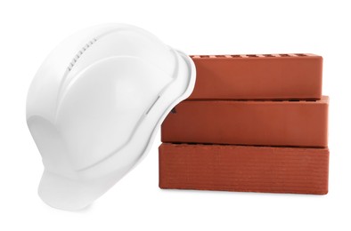 Photo of Hardhat with bricks isolated on white. Construction materials and safety equipment