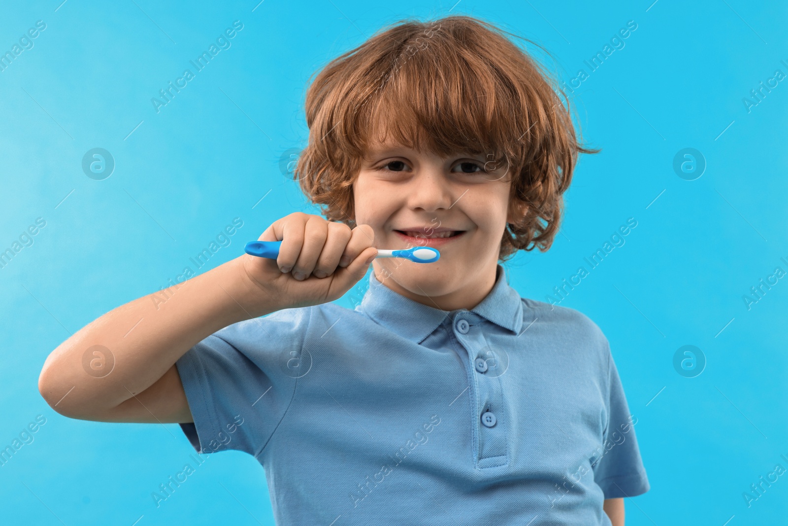 Photo of Cute boy brushing his teeth on light blue background