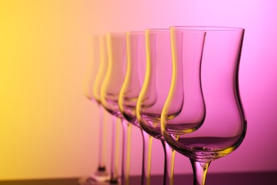 Photo of Empty glasses against color gradient background, closeup