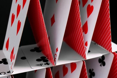 Photo of House of playing cards on black background, closeup