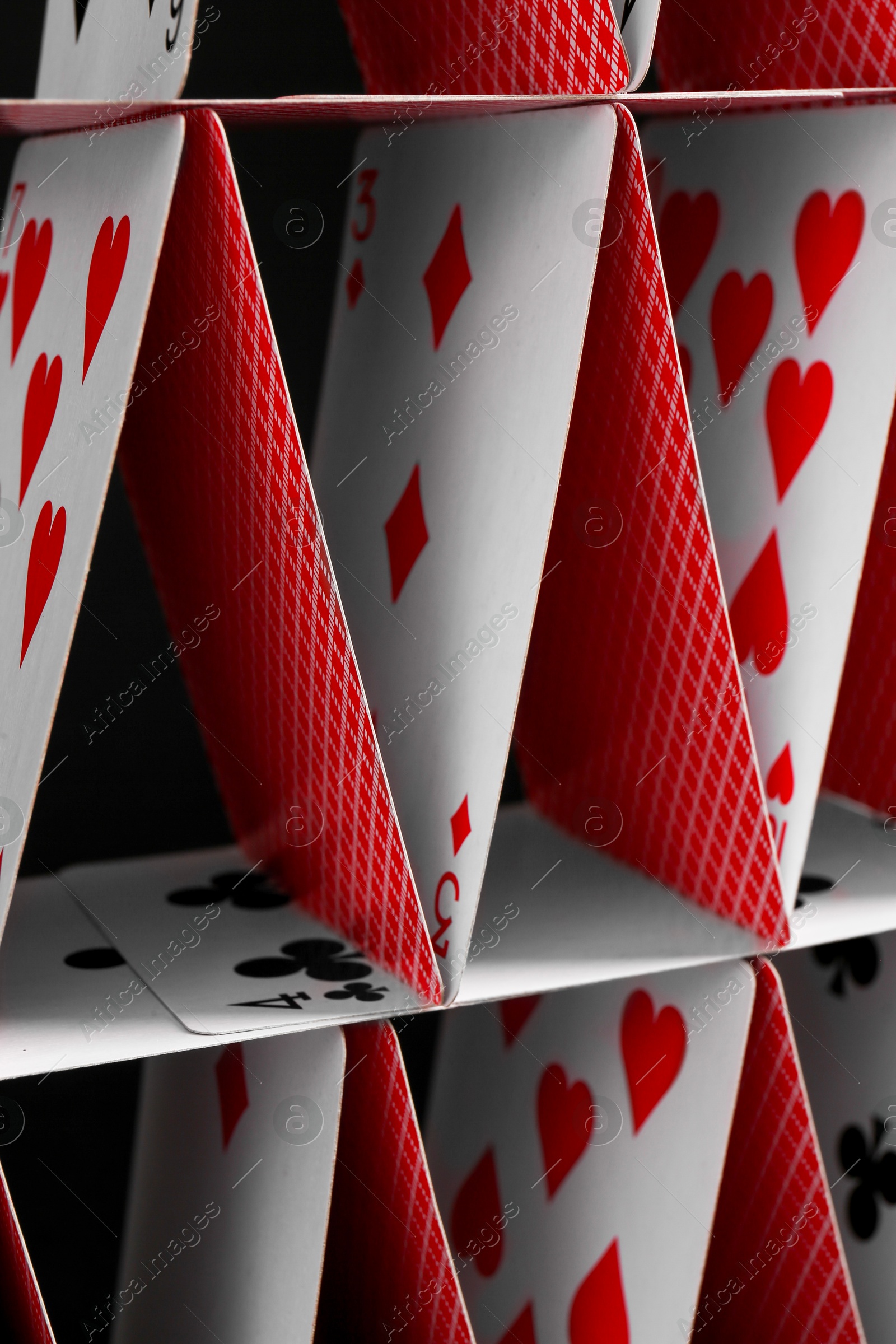 Photo of House of playing cards on black background, closeup