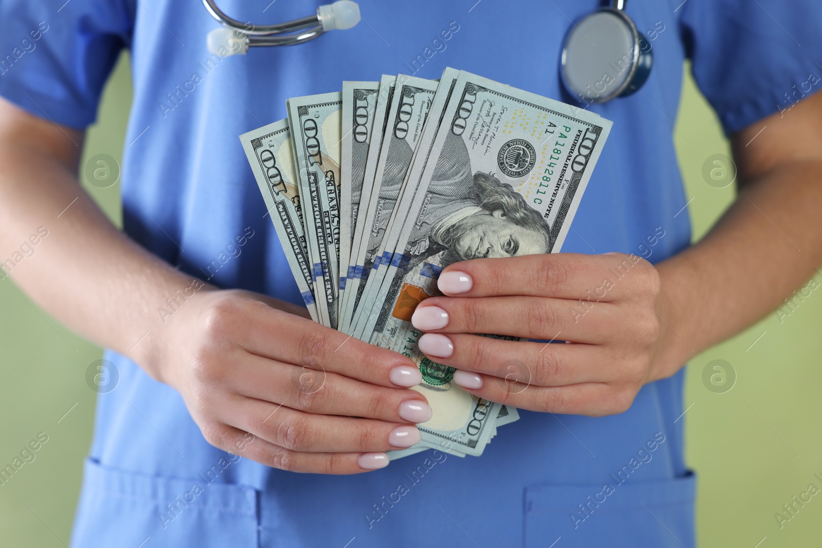 Photo of Corruption concept. Doctor with dollar banknotes on green background, closeup