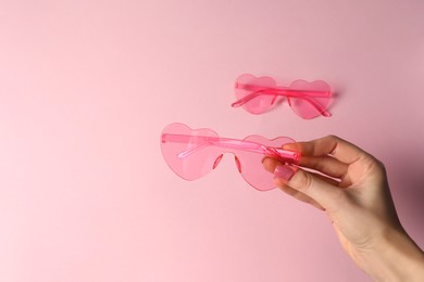 Photo of Woman with stylish heart shaped sunglasses on pink background, closeup. Space for text