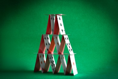 Photo of House of playing cards on green background