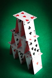 Photo of House of playing cards on green background