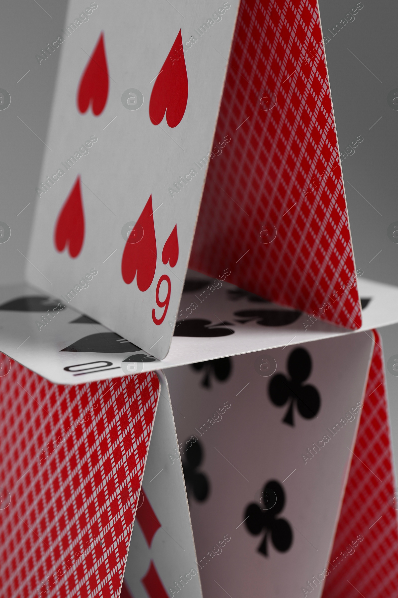 Photo of House of playing cards on grey background, closeup