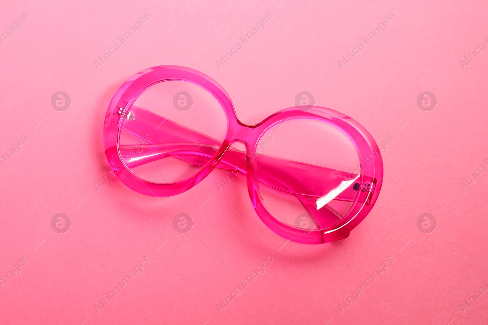 Photo of Stylish bright glasses on pink background, top view