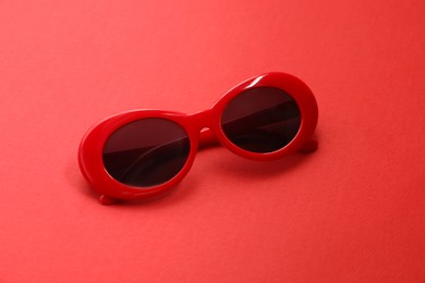 Photo of Stylish sunglasses on red background. Elegant accessory