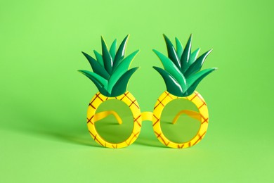 Photo of Creative pineapple shaped sunglasses on green background