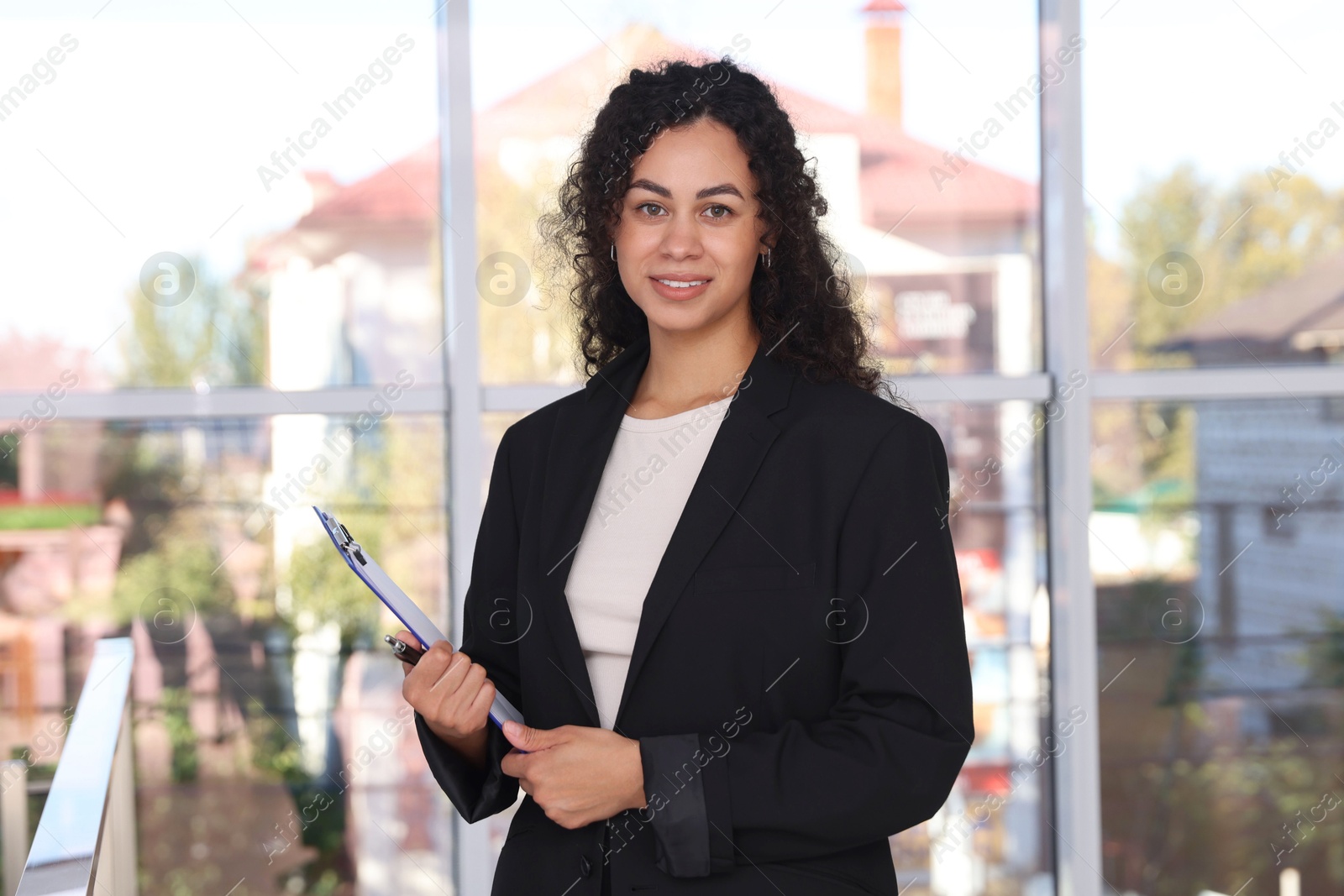 Photo of Portrait of young woman with clipboard wearing stylish suit indoors